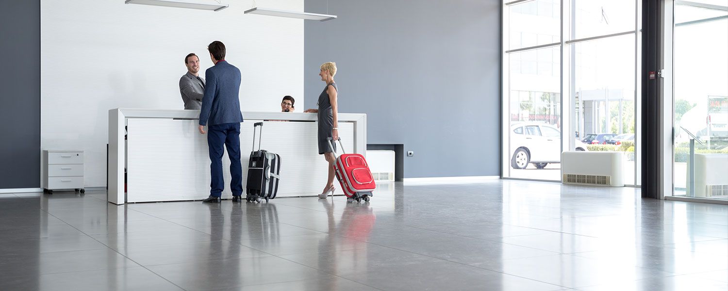 Hotel insurance: A couple checking into a hotel with their suitcases.