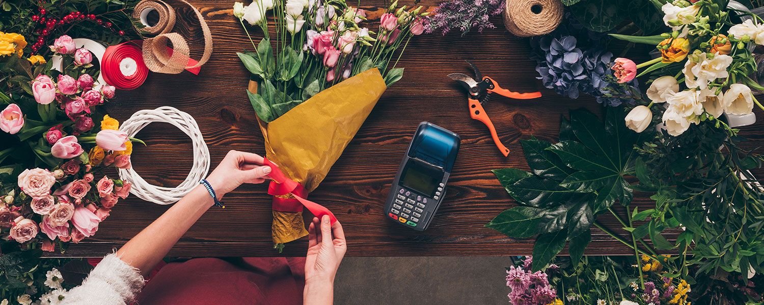 Florist and flower shop insurance: A florist tying a ribbon around a bouquet of flowers. 